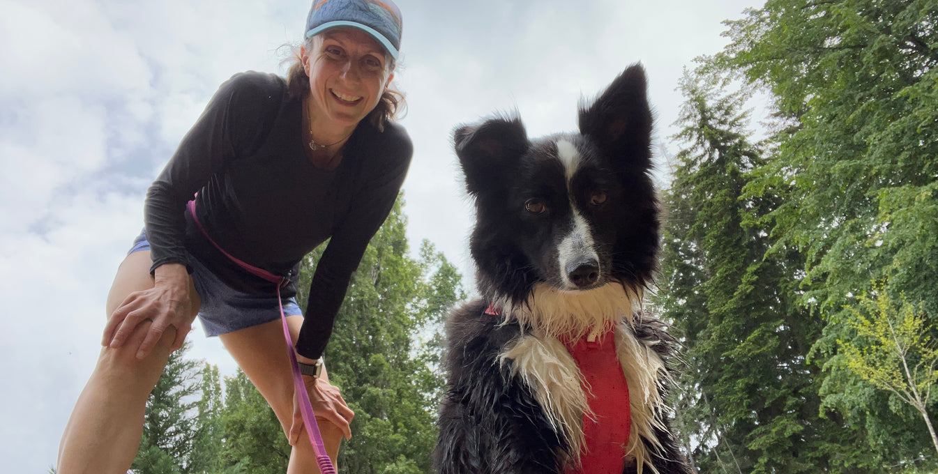 A woman and her dog smile at the camera on a break from running.