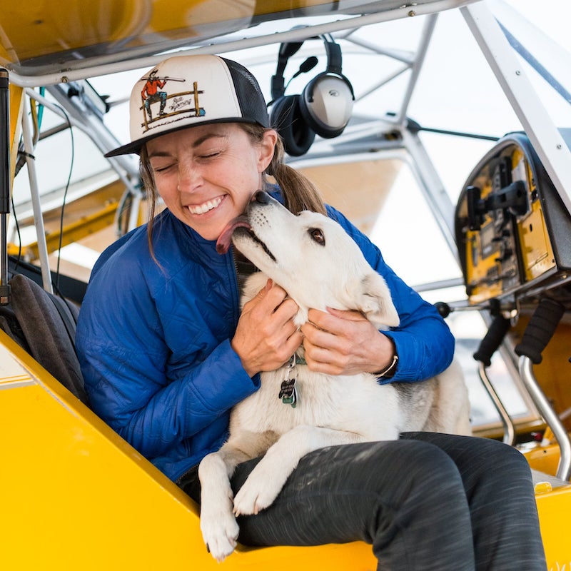 Tala sits in Becca's lap in the cockpit of a plane.
