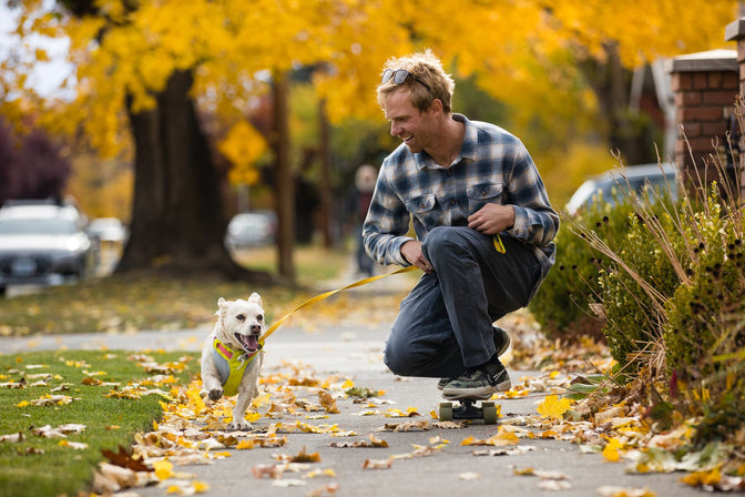 Man skateboards with dog on leash.