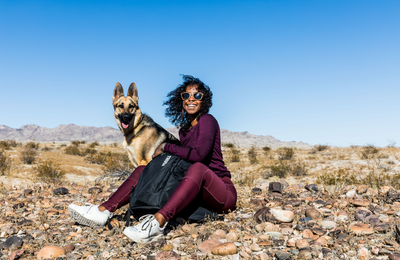 Woman sitting dog and smiling in a desert landscape