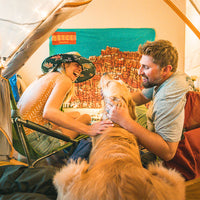 Nate, Dani and Ranger sit inside tent indoors.
