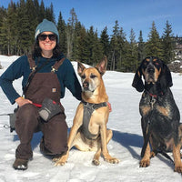 Laura poses with two dogs on the snow.