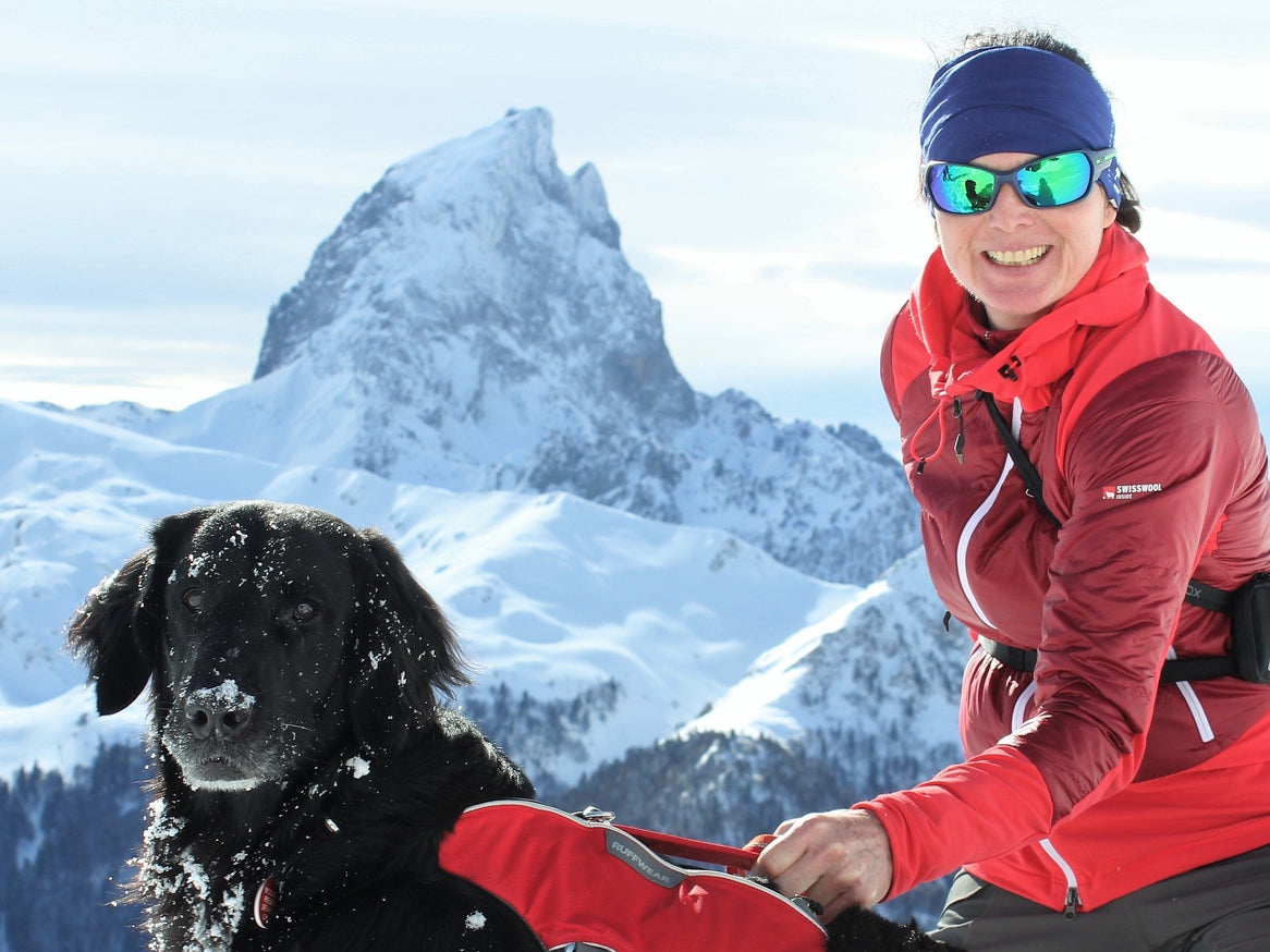 Caroline and her dog Fjord sit atop a snowy ridge in the Alps.