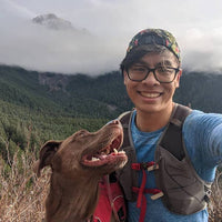 Selfie of Nathan and dog Turkey on a wooded ridge in the mountains while trail running.