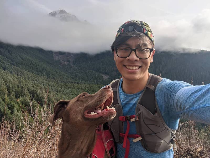 Selfie of Nathan and dog Turkey on a wooded ridge in the mountains while trail running.