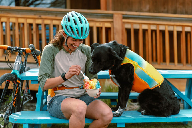 Biker woman eats shaved ice next to dog in shave ice jet stream.