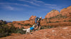 Woman and dogs backpack through red rocks of utah.